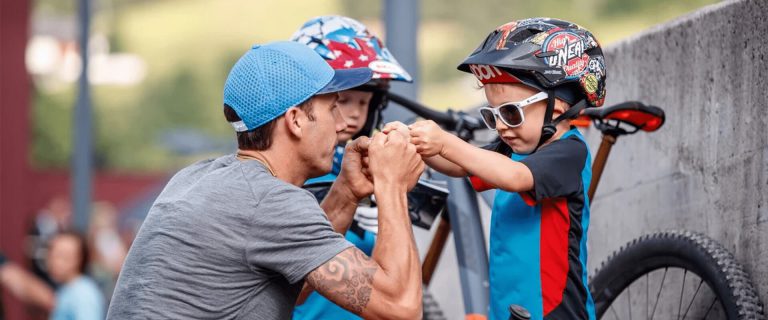 An Adult Motivates Two Children with Bicycle Helmets at the GlemmRide Bike Festival.