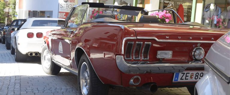 Red Classic Mustang Parked in Front of other Vehicles in Saalbach During the Glemma Rally.