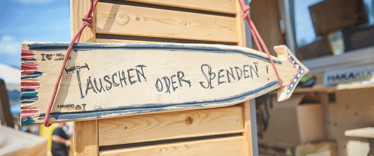 Wooden Sign with the Inscription "Trade or Donate" at the Lake of Charity Charity Event.