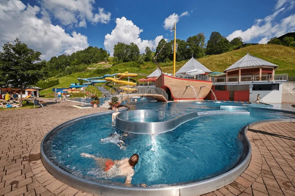 Badespaß im Hotel Wolfgang mit Pool, Rutschen und Panoramaaussicht auf die Bergwelt.