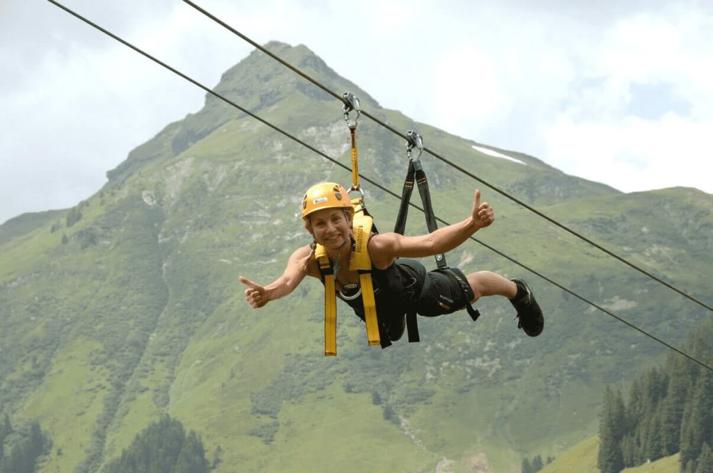 Bergabenteuer am Zipline mit einem fröhlichen Teilnehmer in der Natur von Saalbach-Hinterglemm.