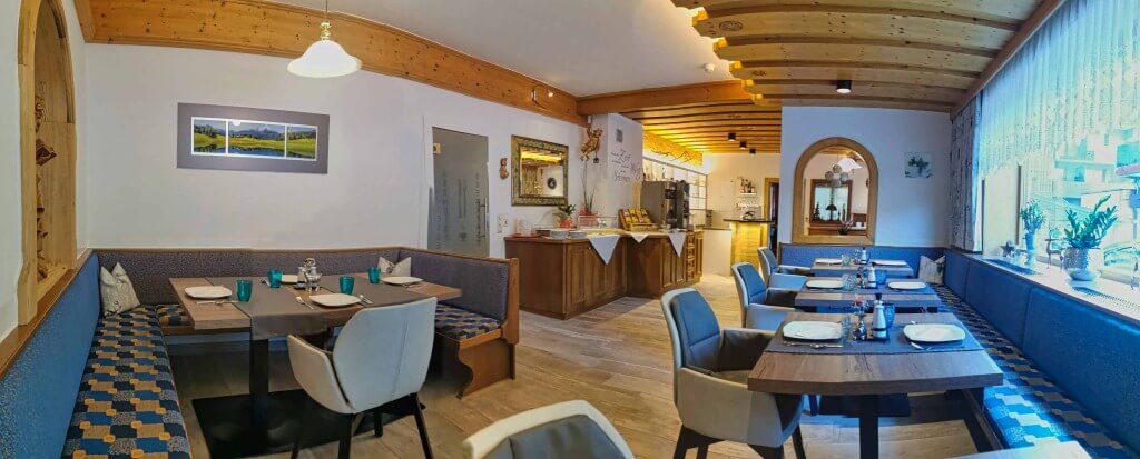 Gemütlicher Frühstücksraum im Hotel Wolfgang mit Holzdecke und moderner Einrichtung.