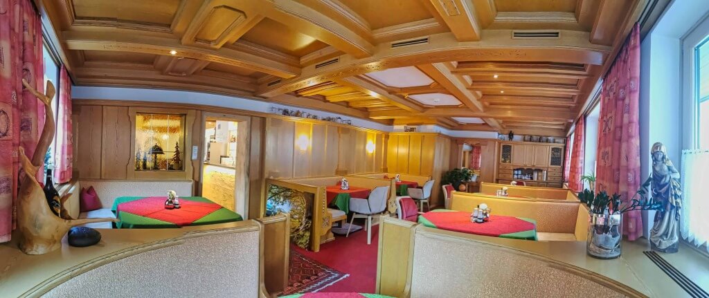 Gemütlicher Speisesaal im Hotel Wolfgang mit Holzverkleidung und bunten Tischdecken.