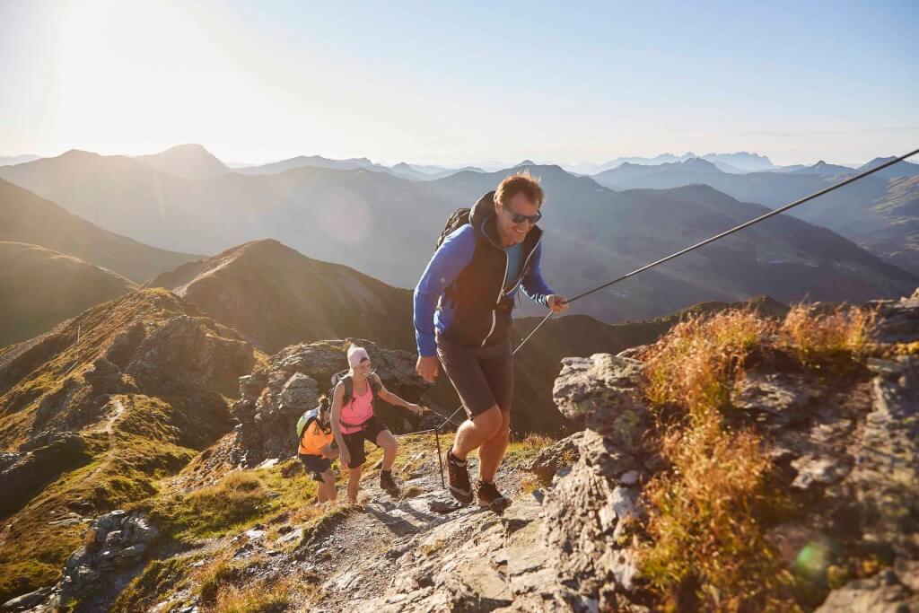 Aktive Wanderer erklimmen einen Berg mit herrlichem Ausblick in Saalbach-Hinterglemm.