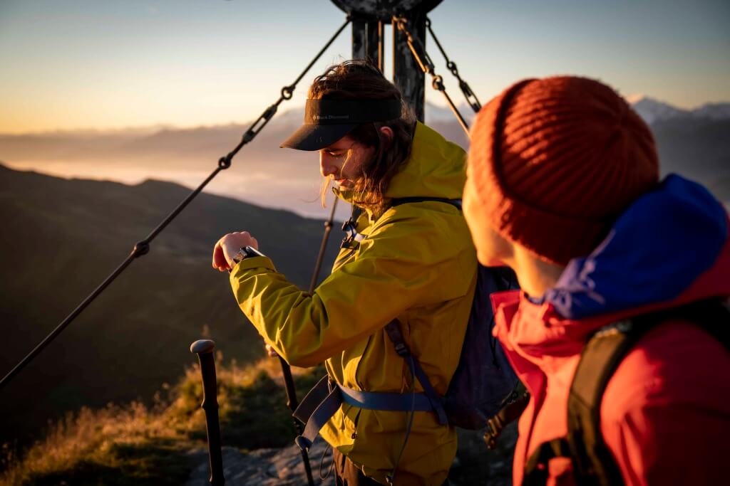 Bergwanderer kontrollieren ihre Ausrüstung bei Sonnenaufgang in traumhafter Natur.